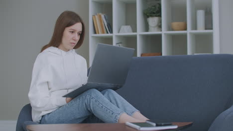 Woman-using-laptop-on-couch-at-home.-Thoughtful-young-woman-sitting-with-computer-on-couch-looking-outside-concentrate-on-work-feeling-bored-need-additional-motivation-working-remotely-at-home.